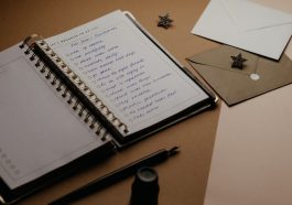 A tidy desk setup featuring a planner, to-do list, envelopes, and a pen.